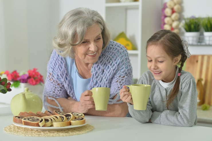 Foto felice donna anziana con nipote con tè a casa