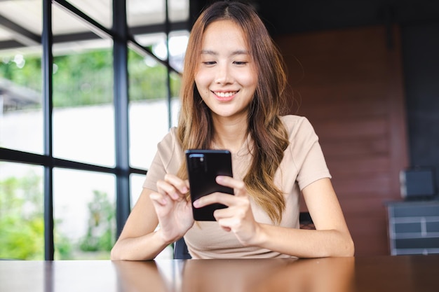 Felice donna asiatica freelance che lavora con dispositivi moderni smartphone mobili al bar Persone che lavorano con la tecnologia e il concetto di dispositivi moderni