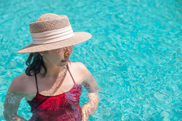 Felice donna asiatica in costume da bagno rosso e cappello di paglia rilassarsi in piscina guardando viewPhangnga Thailandia