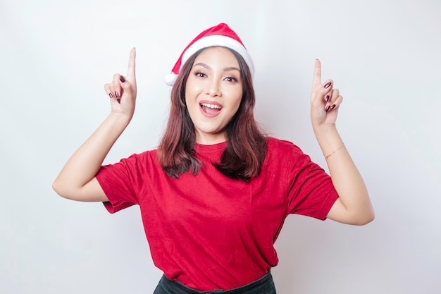 Felice donna asiatica Santa sorride e punta in alto su di lei isolato da uno sfondo bianco Concetto di Natale