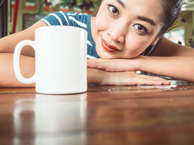 Felice donna asiatica sentirsi assonnato con il caffè del mattino.