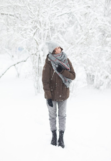 Felice donna attraente in abiti caldi in inverno tempo nevoso all'aperto