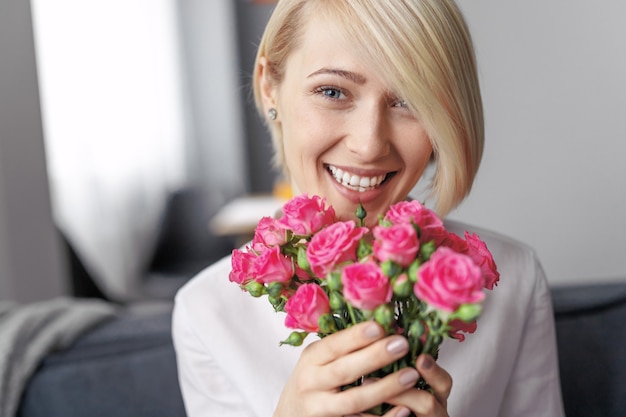 Felice donna bionda che tiene un mazzo di rose