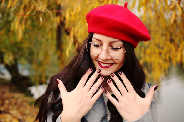 Felice donna bruna in elegante berretto rosso