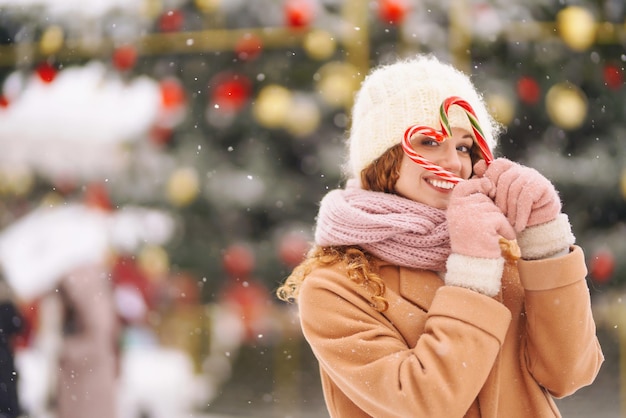 Felice donna carina in posa con le caramelle di Natale Bastoncini di zucchero a strisce di Natale Dolci