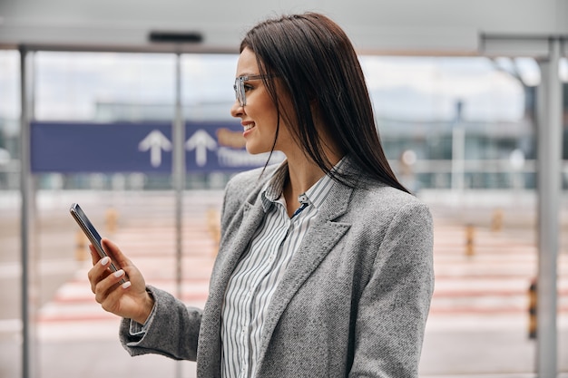 Felice donna caucasica viaggiatrice nel terminal dell'aeroporto con bagagli