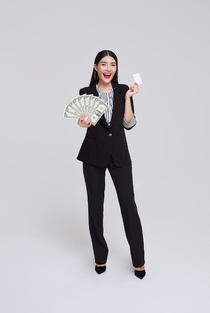 Felice donna d'affari asiatica che mostra la presentazione di carte di credito e soldi dollari sorridendo e ridendo