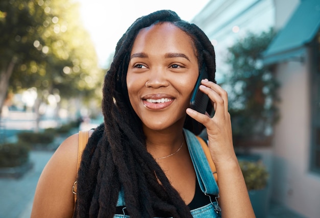 Felice donna di colore per strada telefonata su smartphone e parlando sul marciapiede fuori città Sorridente studente afroamericano comunicazione mobile 5g e connessione per indicazioni stradali