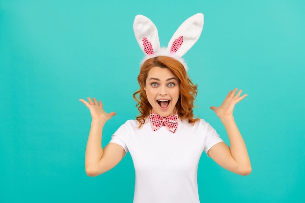 Felice donna di Pasqua stupita in orecchie da coniglio e farfallino su sfondo blu