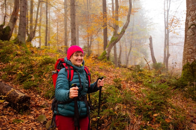 Felice donna escursionista sta camminando nella bellissima foresta autunnale