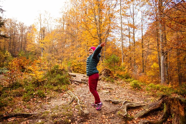 Felice donna escursionista sta camminando nella bellissima foresta autunnale