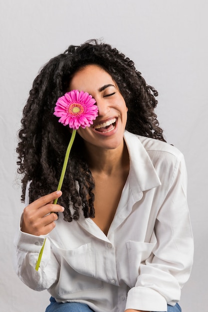 Felice donna etnica con fiore contro gli occhi