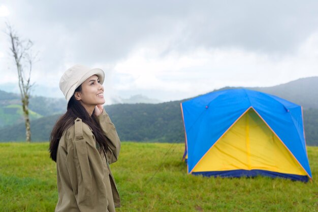 Felice donna in viaggio godendo e rilassarsi vicino alla tenda del campo