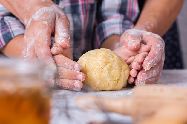 Felice donna matura anziana, nonna e ragazzo, nipote che cucina, impasta la pasta, cuoce la torta, la torta, i biscotti. Tempo in famiglia nell'accogliente cucina. Attività autunnale a casa.