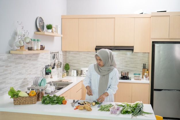 Felice donna musulmana che prepara la cena iftar che cucina da sola in cucina