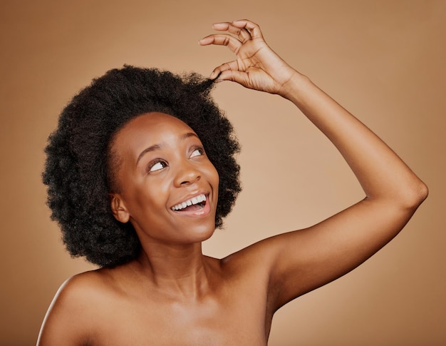 Felice donna nera cura dei capelli e afro naturale per la bellezza in studio isolato su uno sfondo marrone Acconciatura di crescita o eccitato modello africano con cosmetici dopo il trattamento del salone per un sano benessere