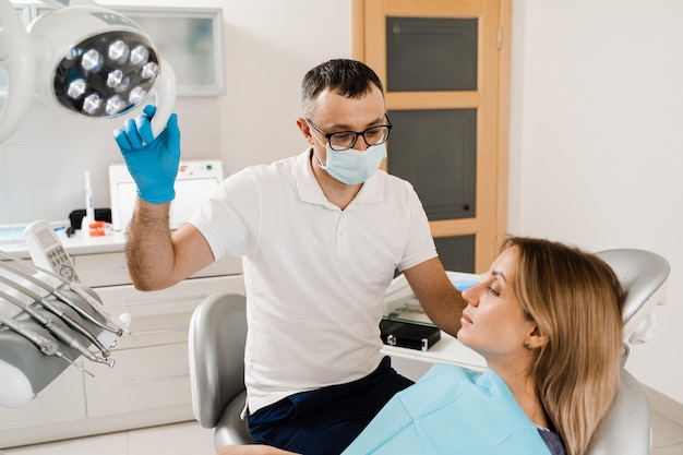 Felice donna paziente di odontoiatria Trattamento dei denti Attraente ragazza seduta in studio dentistico e sorridente Visita e consultazione del dentista