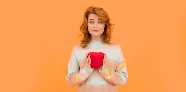 Felice donna rossa con cuore rosso su sfondo arancione con copia spazio San Valentino