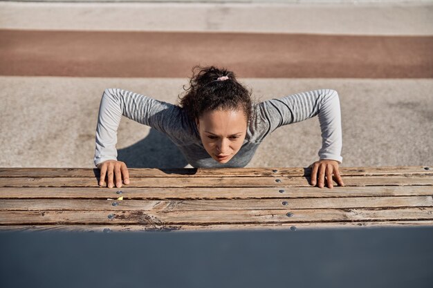 Felice donna sana e sportiva sta facendo allenamenti di allenamento in una giornata di sole