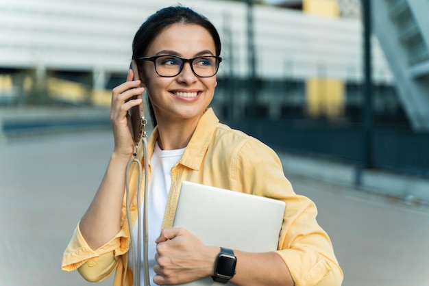 Felice donna soddisfatta che parla o chiacchiera con qualcuno al suo smartphone mentre distoglie lo sguardo con un sorriso di piacere. Foto d'archivio