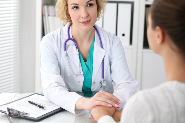 Felice dottoressa bionda che guarda il paziente mentre le parla e rassicura Medicina assistenza sanitaria e concetto di aiuto