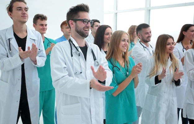 Felice dottoressa in piedi tra i suoi colleghi che applaudono