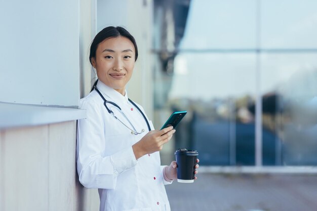 Felice dottoressa sorridente e gioiosa La donna asiatica usa il telefono