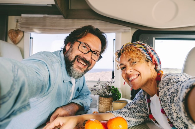 Felice e allegro, fiducioso, coppia uomo e donna sorridono e si divertono a scattare foto di selfie all'interno di un moderno e accogliente camper Turistico e vanlifers persone godono di libertà, felicità insieme in vacanza