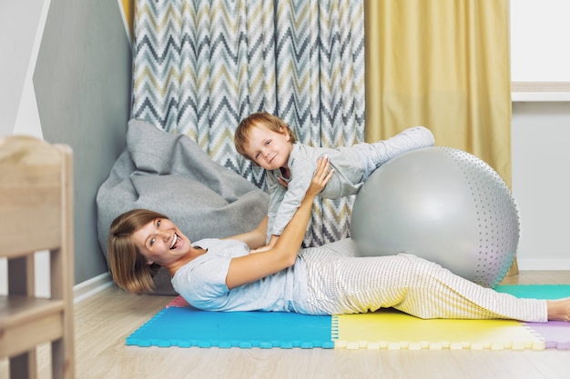 Felice e bella madre e figlio, la famiglia insieme fa l'allenamento con la palla da ginnastica