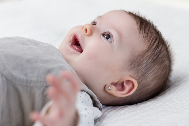 Felice e carina bambina sdraiata sulla schiena sopra il copriletto bianco