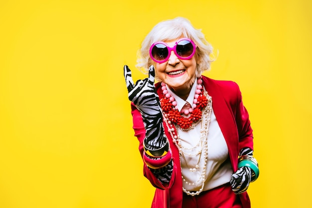 Felice e divertente vecchia signora con vestiti alla moda ritratto su sfondo colorato Nonna giovanile con concetti di stile stravaganti sull'anzianità di vita e sugli anziani