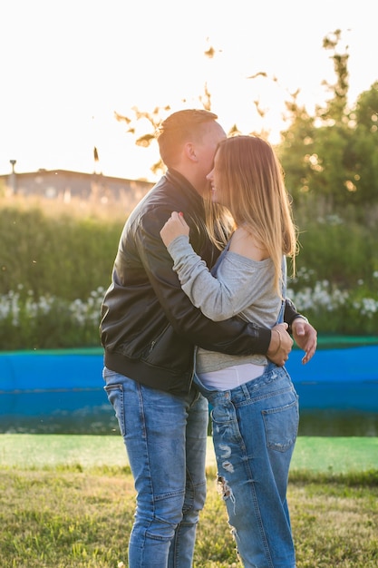 Felice e giovane coppia incinta che si abbraccia nella natura