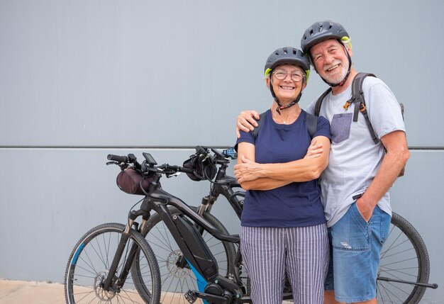 Felice e rilassata coppia caucasica senior con casco godendo attività sportiva con biciclette elettriche nel concetto di mobilità sostenibile all'aperto