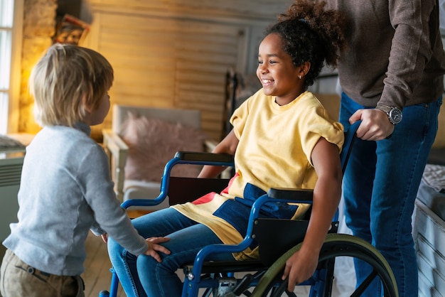 Felice famiglia amorevole multietnica. Bambina sorridente con disabilità in sedia a rotelle a casa