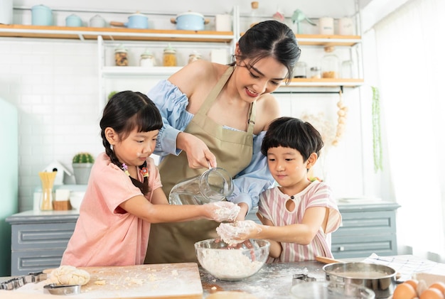 Felice famiglia asiatica che prepara la pasta e cuoce i biscotti in cucina a casa Godetevi la famiglia
