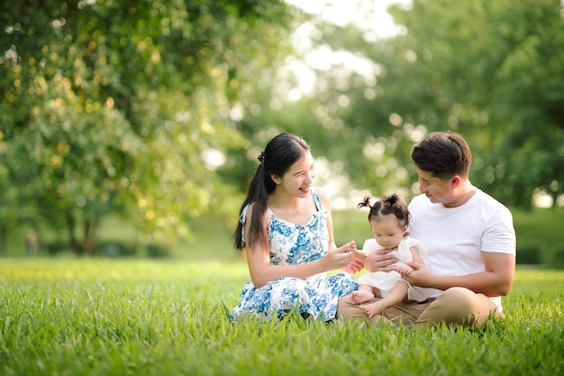 Felice famiglia asiatica padre madre e figlia piccola che giocano nel parco godendosi la splendida natura al tramonto Buon concetto di vacanze in famiglia