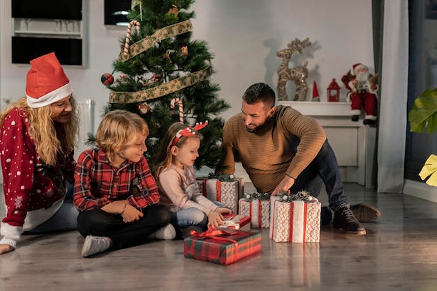 Felice famiglia di quattro persone che condividono i regali di Natale