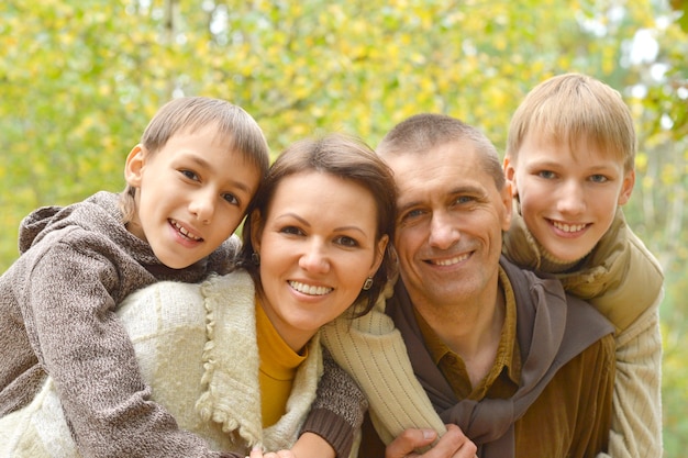 Felice famiglia di quattro persone che stanno insieme nel parco in autunno