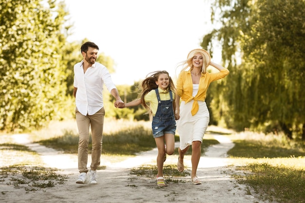 Felice famiglia di tre persone in esecuzione godendo di una passeggiata all'aperto in campagna