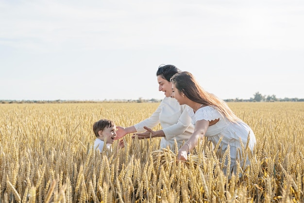 Felice famiglia di tre persone madre e due bambini che camminano sul campo di grano