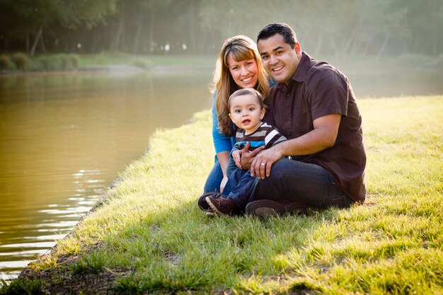 Felice famiglia etnica di razza mista che posa per un ritratto nel parco vicino al lago