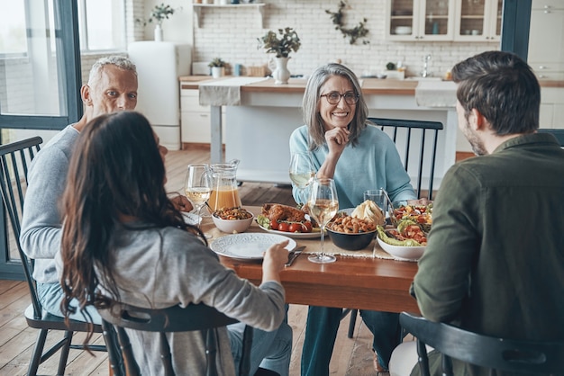 Felice famiglia multigenerazionale che comunica e sorride mentre cena insieme