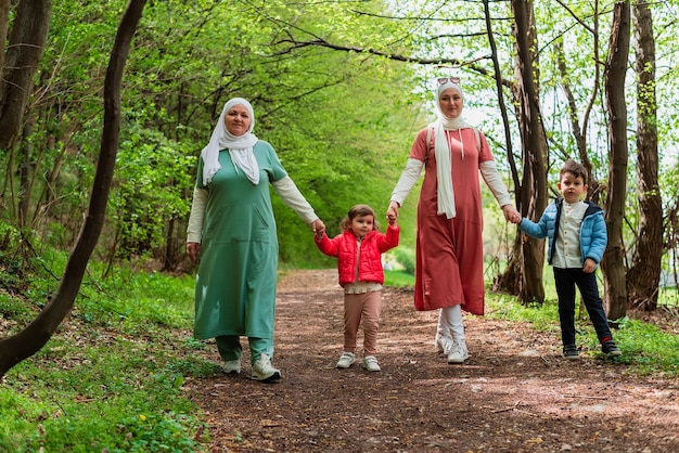 Felice famiglia musulmana madre con una nonna che tiene le mani dei bambini mentre cammina nella foresta