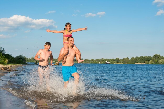 Felice famiglia padre figlio piccola figlia corre insieme lungo la spiaggia Vacanze di viaggio stile di vita