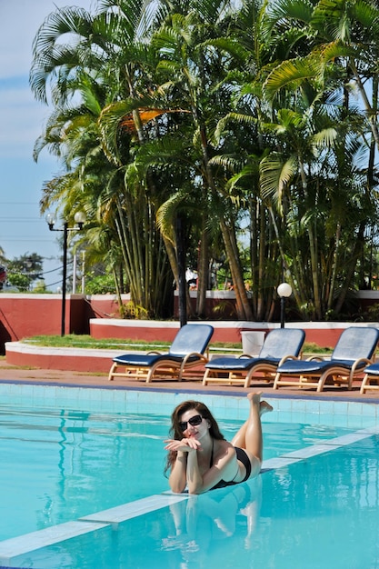 Felice femmina sdraiata da una piscina in bikini