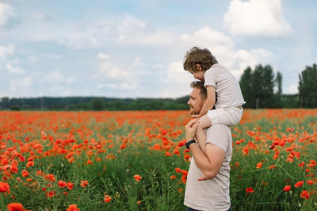 Felice festa del papà, il ragazzino e il padre stanno giocando in un bellissimo campo di papaveri rossi