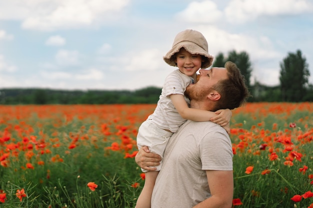 Felice festa del papà, il ragazzino e il padre stanno giocando in un bellissimo campo di papaveri rossi