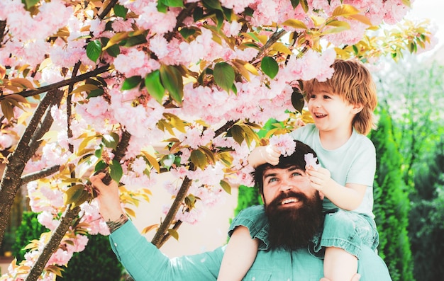 Felice festa del papà padre che dà al figlio un giro sul retro nel concetto di infanzia felice del parco