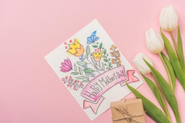Felice festa della mamma biglietto di auguri confezione regalo e tulipani bianchi su sfondo rosa
