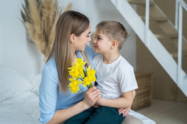 Felice festa della mamma piccolo figlio regala fiori alla mamma fiori nelle mani di un ragazzo